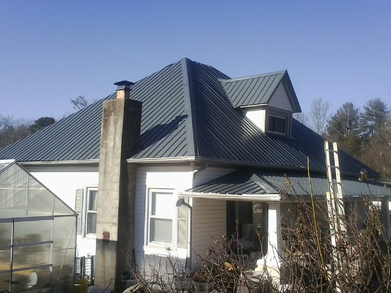 Dark blue standing seam metal roof on a white farmhouse with dormer — Slate & Tile Roof Repair by Roofing Brothers in Elburn