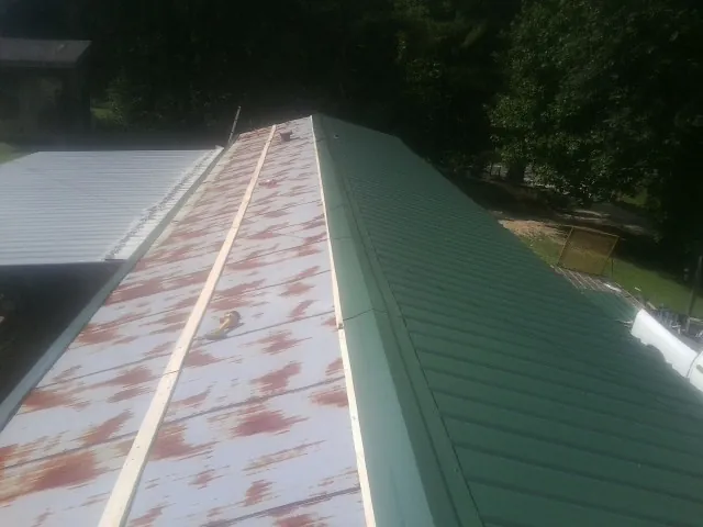 Old rusted panels beside newly installed green metal roofing — Wind Damage Roof Repair by Roofing Brothers in Elburn