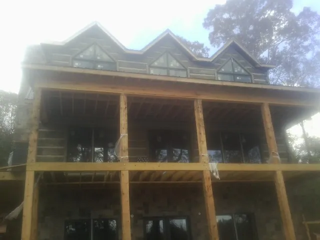 Dormers and porch framing on a large log home under construction — Roof Coating work by our crew in Elburn