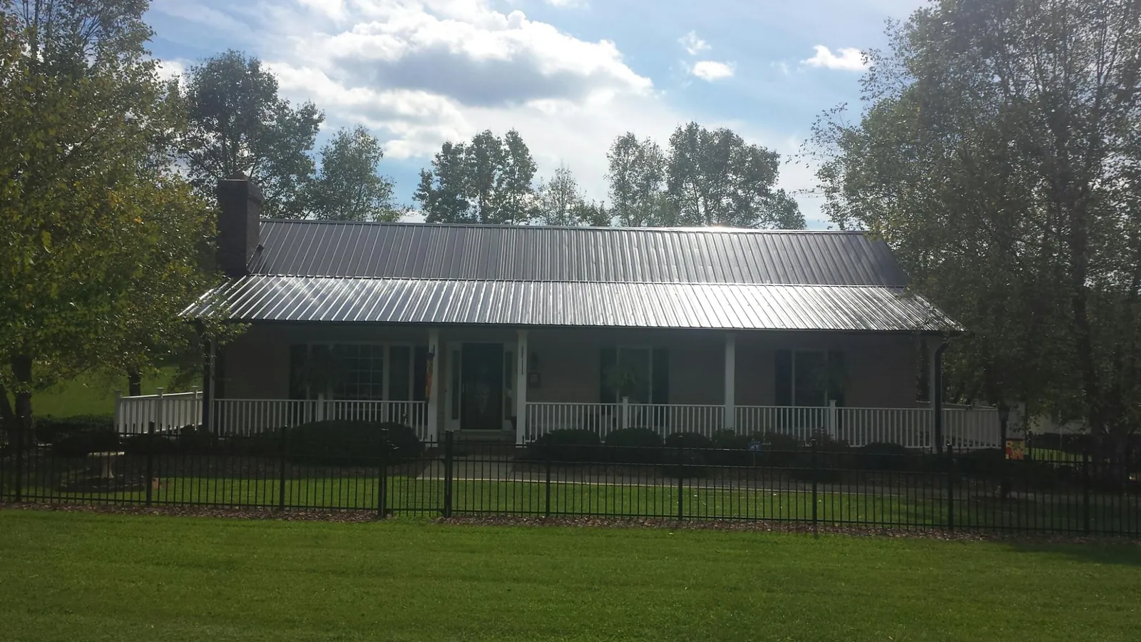 Gray metal roof on a brick ranch with a full width front porch — Gutter Guard Installation work by our crew in Elburn