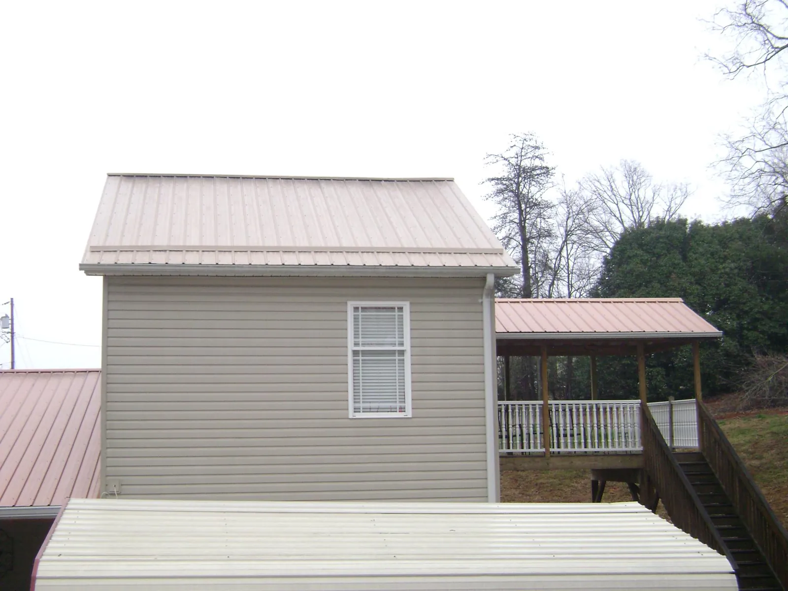 Tan metal roofs on a two story addition and attached porch, from a Roof Replacement job in Elburn