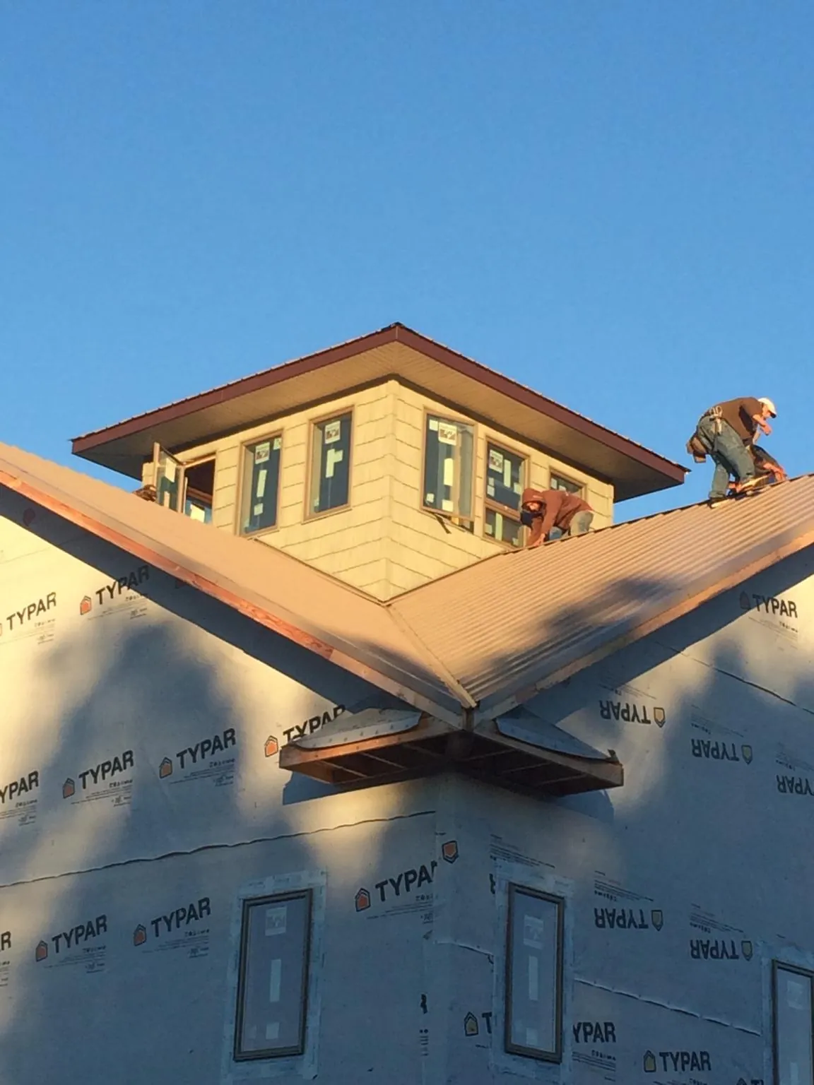 Roofers working around a rooftop cupola on a new metal roof at sunset — Roof Waterproofing in Elburn by Roofing Brothers